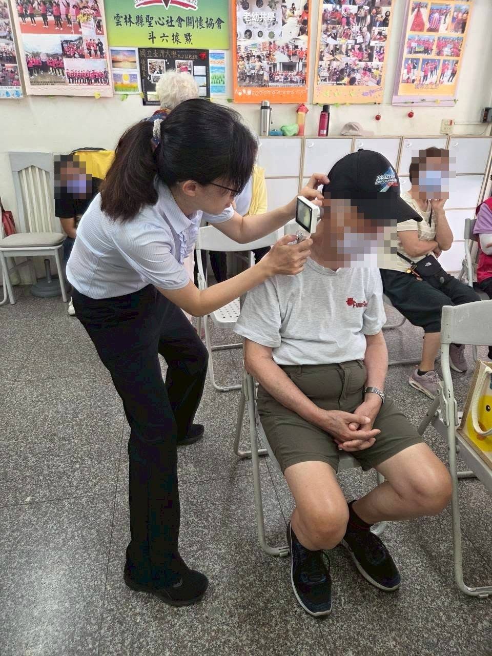 聽力師拿手持式儀器為一位長輩做耳道檢視